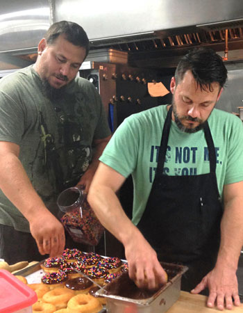 Hugs and Donuts founders Jason Hill and Matt Opaleski pepare for the morning rush